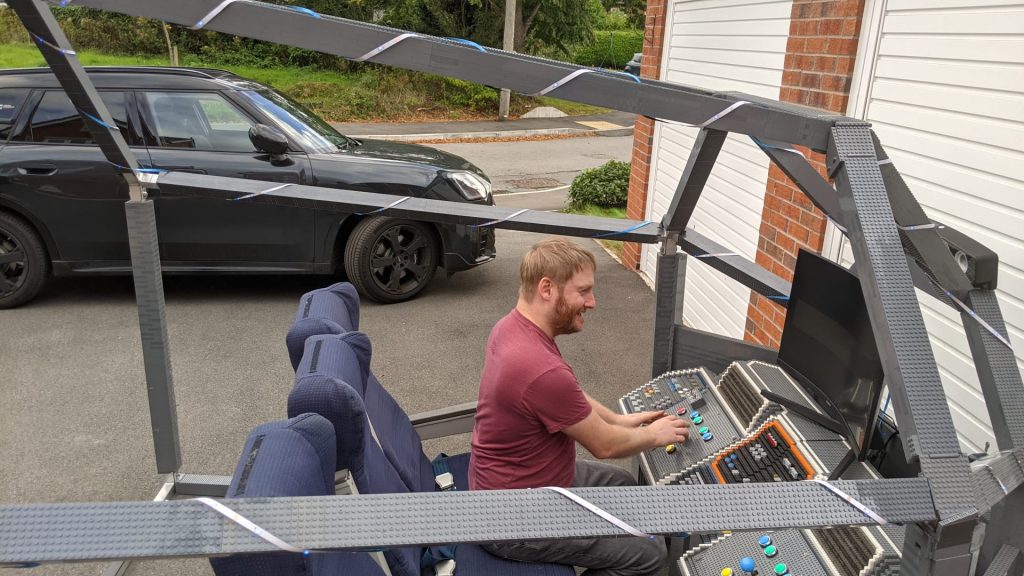 Nick Saunders seated at the arcade controls of the restored BRICKLIVE cockpit simulator